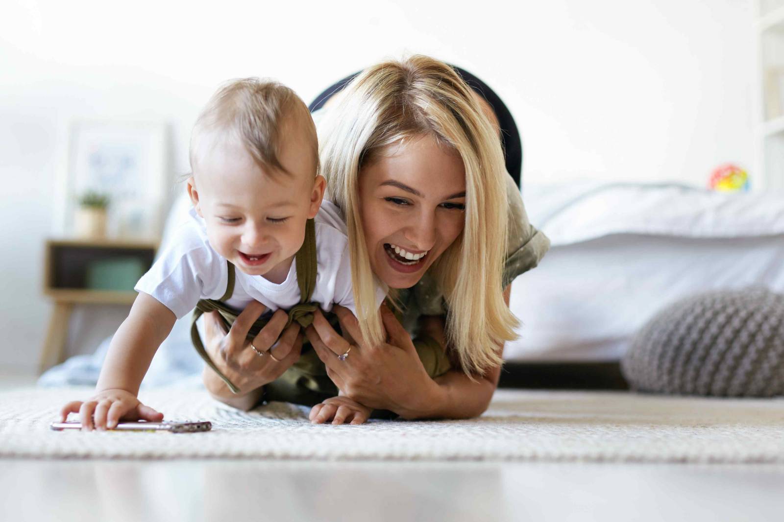 A mother and her baby laughing together on the floor